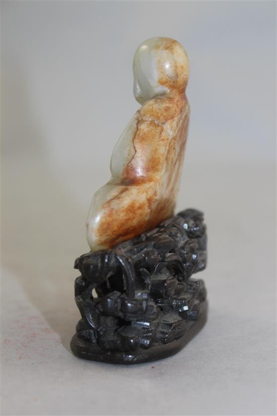 A Chinese white and russet jade carving of a luohan, 18th / 19th century, 6.7cm, neck broken and restuck, intricately carved rosewood s